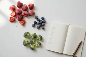 Frozen strawberries, blueberries and broccoli samples with a buyer evaluation notebook on a white table