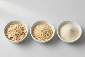 Dehydrated garlic flakes, granules and powder in three white bowls