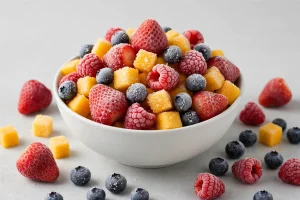 Frozen fruit medley with frost crystals in a white bowl